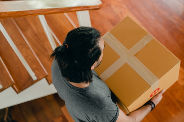 man walking up stairs holding a brown box