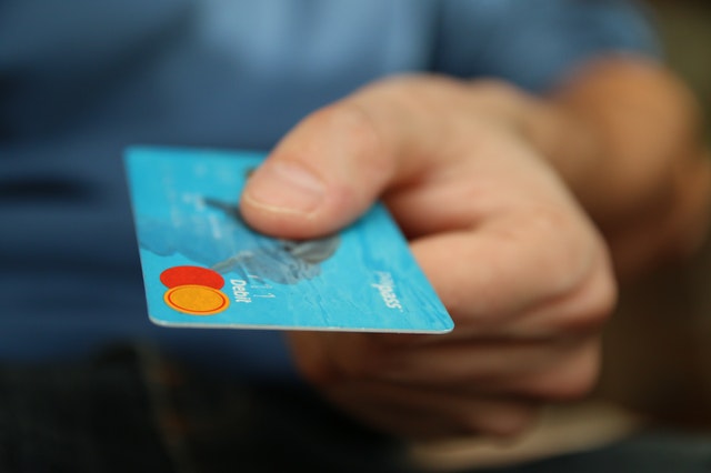 person holding out a blue debit card